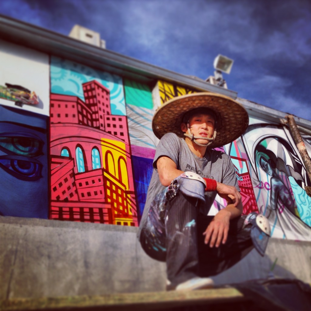 John Park crouching near a series of his own murals located in Los Angeles.