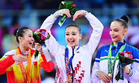 Son Yeon-jae, center, makes a heart-shape with her arms after winning South Korea's first-ever Asiad gold in the individual all-around event at the Namdong Gymnasium in Incheon, Thursday. China's Deng Senyue, left, won the silver, while Anastasiya Serdyukova of Uzbekistan settled for bronze. (Korea Times photo by Shim Hyun-chul)