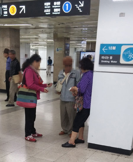Two "Bacchus women" are seen attempting to sell counterfeit Viagra pills to an elderly man at Jongno 5-ga Station in central Seoul. (Korea Times)