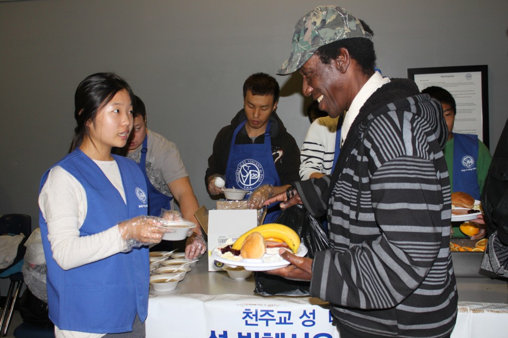 A Korean teenager serves homemade soup to a homeless man at the special Thanksgiving breakfast. 