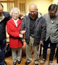 This photo provided by Derek Sciba shows Kenneth Bae, center, and his mother Myunghee Bae, in red coat, praying with other family members after his release from North Korea, Saturday Nov. 8, 2014.  (AP Photo/Derek Sciba)
