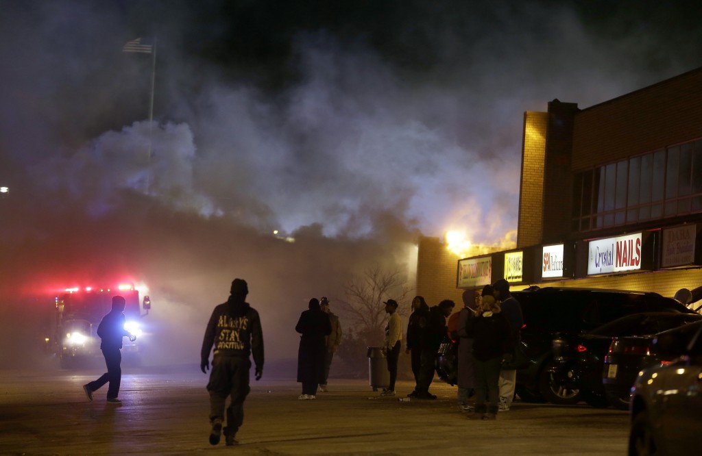 Smoke fills the streets as some buildings are on fire after the announcement of the grand jury decision Monday, Nov. 24, 2014, in Ferguson, Mo. A grand jury has decided not to indict Ferguson police officer Darren Wilson in the death of Michael Brown, the unarmed, black 18-year-old whose fatal shooting sparked sometimes violent protests. (AP Photo/Jeff Roberson)