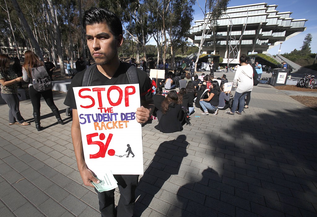 Several hundred UCSD students gathered on the walkway in front of Geisel Library in a sit-in to protest a proposed hike in tuition of up to five percent for the next five years.|Andrew Villalobos carries a sign prior to a sti-in of UCSD students.  A senior graduating with a B.S. in engineering, he is worried about his brother and sister, both in high school and what this might mean for them if they choose to attend a UC school. ( AP - John Gastaldo/U-T San Diego/Zuma Press)