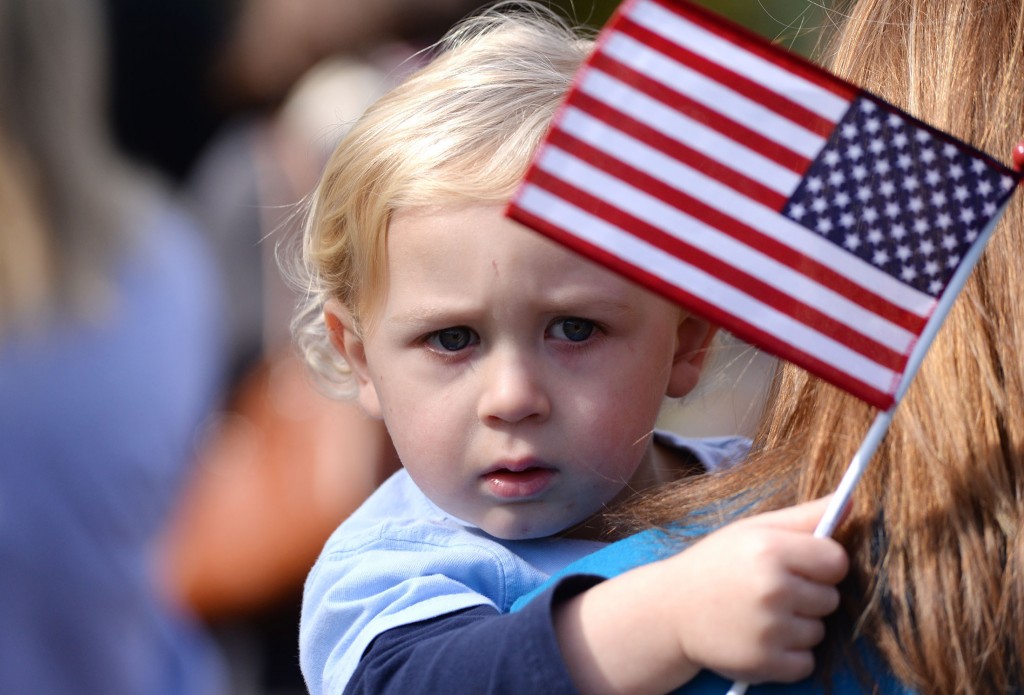 Parker Southerland, 1, waves a flag toward retired service dogs gathered at Pearson Park in Kinston, N.C., following a veteran's parade on Saturday, Nov. 8, 2014.(AP Photo/Daily Free Press, Zach Frailey)