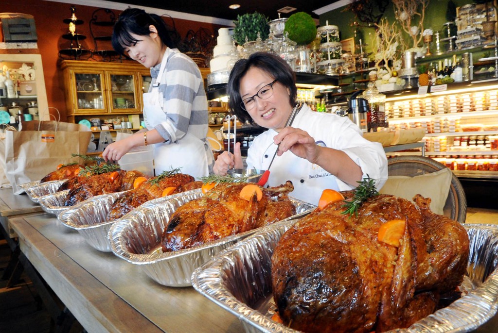 Banchan A La Carte Owner Jane Chang, right, and an employee prepare Thanksgiving turkeys ordered by Korean Americans Wednesday. (Park Sang-hyuk/The Korea Times)