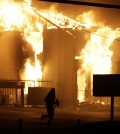 A man runs away from the burning storage facility after  the announcement of the grand jury decision Monday, Nov. 24, 2014, in Ferguson, Mo. A grand jury has decided not to indict Ferguson police officer Darren Wilson in the death of Michael Brown, the unarmed, black 18-year-old whose fatal shooting sparked sometimes violent protests. (AP Photo/David Goldman)