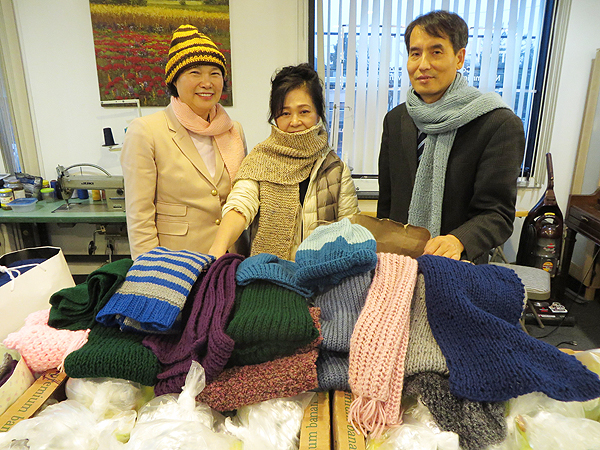 New Jersey ___ President Paul Yoon stands with center employees and hand-knitted scarves and hats to be given out to local homeless this Christmas.
