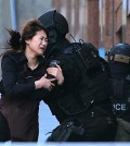 A hostage runs to armed tactical response police officers for safety after she escaped from a cafe under siege at Martin Place in the central business district of Sydney, Australia, Monday, Dec. 15, 2014. New South Wales state police would not say what was happening inside the cafe or whether hostages were being held. But television footage shot through the cafe's windows showed several people with their arms in the air. (AP Photo/Rob Griffith)