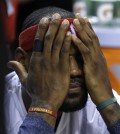 Cleveland Cavaliers forward LeBron James covers his face while sitting on the bench before an NBA basketball game against the Miami Heat, Thursday, Dec. 25, 2014, in Miami. (AP Photo/Lynne Sladky)
