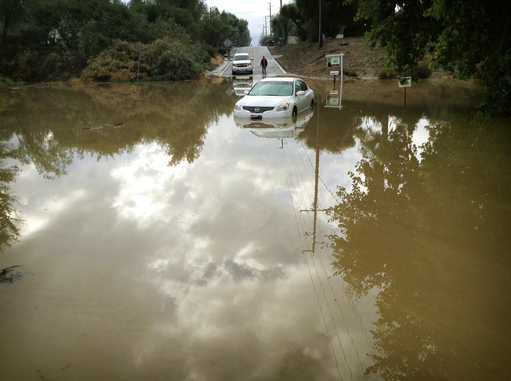 A car sits partially submerged in flood waters on Hemet Street in Hemet, Calif., Thursday morning, Dec. 4, 2014, after overnight rains doused the area.  A second day of much-needed rain is falling across drought-stricken California. (AP Photo/The Press-Enterprise, Craig Shultz ) 