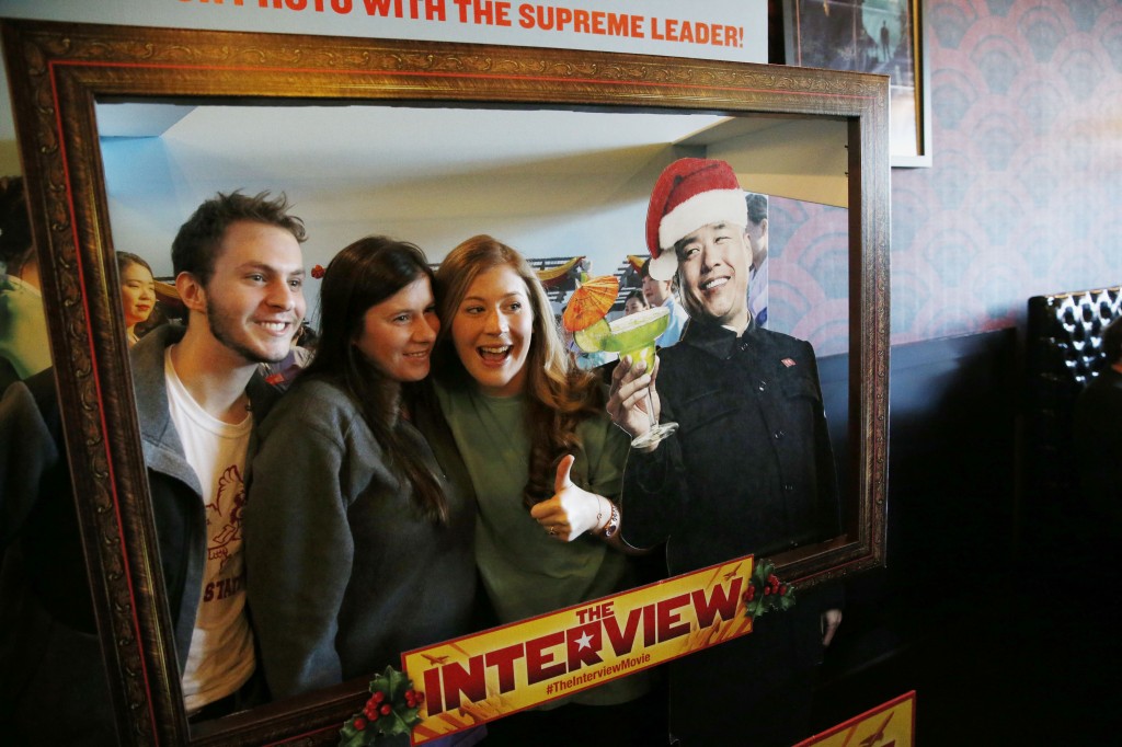 Christmas Day moviegoers take a photograph with an advertisement for the film "The Interview" that is playing at the Alamo Drafthouse Cinema in Richardson, Texas, Thursday, Dec. 25, 2014. The film's Christmas Day release was canceled by Sony after threats of violence by hackers linked to North Korea, but the release was reinstated in some independent theaters and through a variety of digital platforms. (AP Photo/The Dallas Morning News, Andy Jacobsohn)