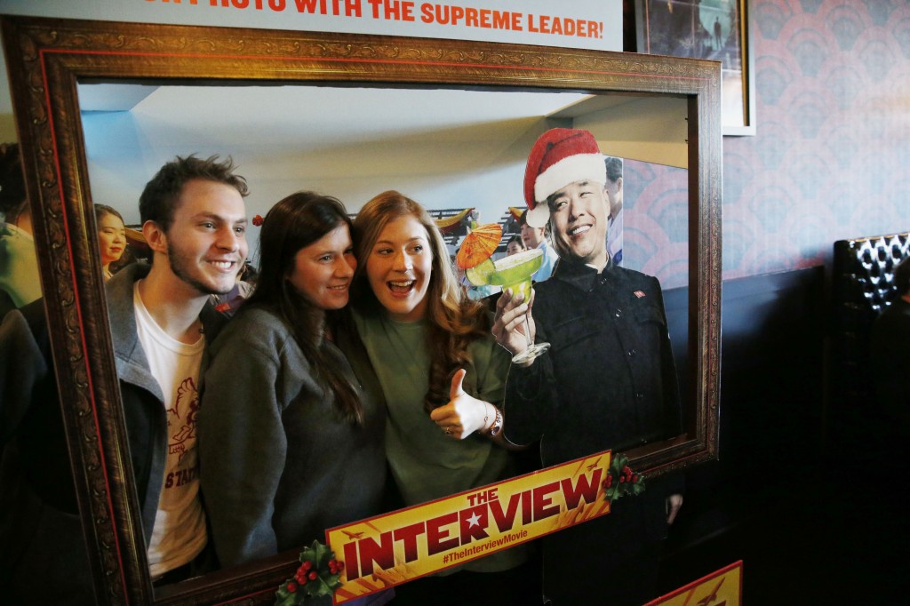 Christmas Day moviegoers take a photograph with an advertisement for the film "The Interview" that is playing at the Alamo Drafthouse Cinema in Richardson, Texas, Thursday, Dec. 25, 2014. The film's Christmas Day release was canceled by Sony after threats of violence by hackers linked to North Korea, but the release was reinstated in some independent theaters and through a variety of digital platforms. (AP Photo/The Dallas Morning News, Andy Jacobsohn)  