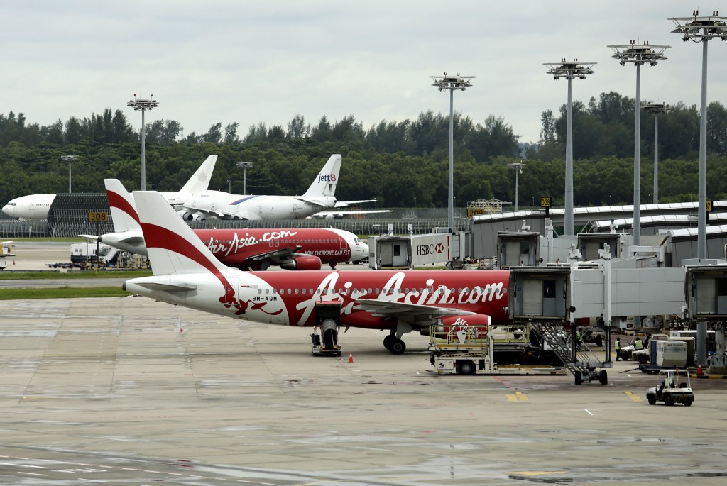 An AirAsia plane taxis, while another is parked on the tarmac at the Changi International Airport on Monday, Dec. 29, 2014 in Singapore. Search planes and ships from several countries on Monday were scouring Indonesian waters over which an AirAsia jet disappeared, more than a day into the region's latest aviation mystery. AirAsia Flight 8501 vanished Sunday in airspace thick with storm clouds on its way from Surabaya, Indonesia, to Singapore. (AP Photo/Wong Maye-E)