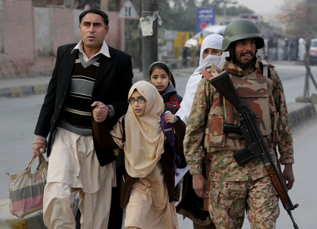 Pakistani parents escort their children outside a school attacked by the Taliban in Peshawar, Pakistan, Tuesday, Dec. 16, 2014. Taliban gunmen stormed a military-run school in the northwestern Pakistani city of Peshawar on Tuesday, killing and wounding scores, officials said, in the highest-profile militant attack to hit the troubled region in months. (AP Photo/B.K. Bangash)