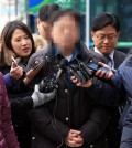 The 53-year-old professor at Seoul National University (C) is questioned by reporters before attending a prosecution probe into sexual abuse charges on Dec. 3, 2014. (Yonhap)
