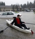 A man uses a kayak to make his way around a flooded parking lot at a shopping center Thursday, Dec. 11, 2014, in Healdsburg, Calif.  A powerful storm churned through Northern California Thursday, knocking out power to tens of thousands and delaying commuters while soaking the region with much-needed rain. (AP Photo/Eric Risberg)