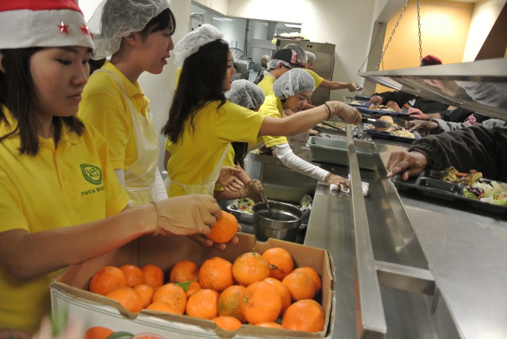 PAVA World student volunteers give out food to the homeless at Midnight Mission Saturday. (Park Ji-hye/The Korea Times)