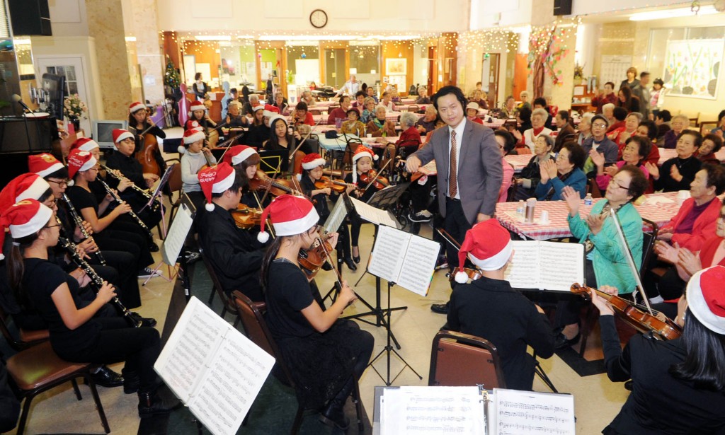 Hayfield Youth Orchestra, led by conductor KIm Yong-jae, performs at Wilshire Day Care Center Monday. (Park Sang-hyuk/The Korea Times)