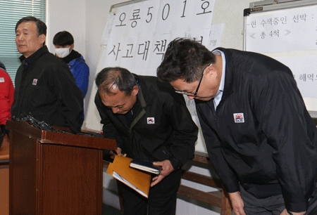 ajo Industries officials bow in apology as the company's CEO, Kim Jeong-su, left, stands nearby at the firm's offices in Busan, Tuesday. (Yonhap)