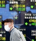 A man passes by an electronic stock board of a securities firm in Tokyo, Tuesday, as Asian stocks mostly fell on concern about feeble Chinese trade figures, Japan's recession and weaker-than-expected German industrial growth. The Japanese yen is expected to weaken further at a faster rate against the won, making Korean exports less competitive. (AP)