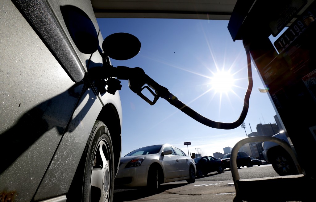 Vehicles form a line behind a motorist gassing up at a gas station where the cash price for regular unleaded is listed at $1.71, Friday, Jan. 23, 2015, in Newark, N.J. For the first time since 2009, most Americans are paying less than $2 a gallon. (AP Photo/Julio Cortez)