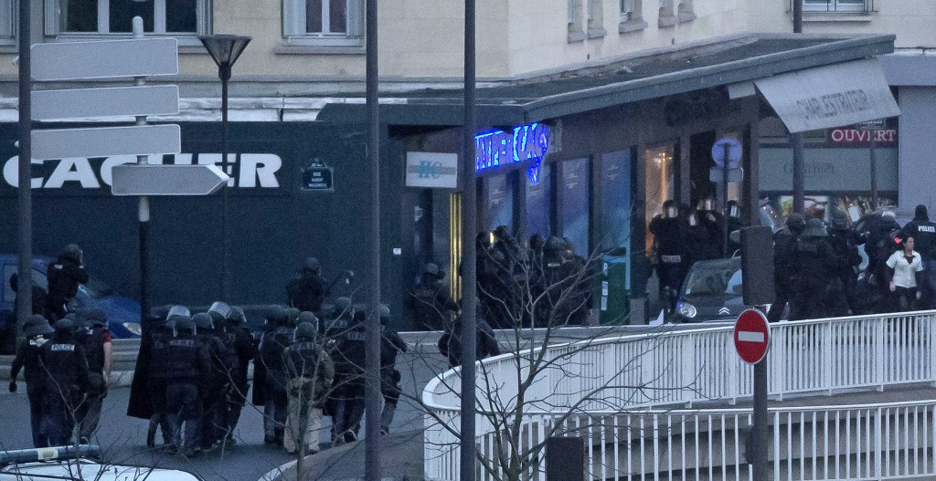 French police officers storm a kosher grocery to end a hostage situation, Paris, Friday, Jan. 9, 2015. Explosions and gunshots were heard as police forces stormed a kosher grocery in Paris where a gunman was holding at least five people hostage. (AP Photo/Michel Euler)