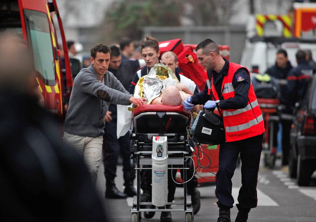 An injured person is transported to an ambulance after a shooting, at the French satirical newspaper Charlie Hebdo's office, in Paris, Wednesday, Jan. 7, 2015. Masked gunmen stormed the offices of a French satirical newspaper Wednesday, killing at least 11 people before escaping, police and a witness said. The weekly has previously drawn condemnation from Muslims. (AP Photo/Thibault Camus)