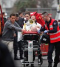 An injured person is transported to an ambulance after a shooting, at the French satirical newspaper Charlie Hebdo's office, in Paris, Wednesday, Jan. 7, 2015. Masked gunmen stormed the offices of a French satirical newspaper Wednesday, killing at least 11 people before escaping, police and a witness said. The weekly has previously drawn condemnation from Muslims. (AP Photo/Thibault Camus)