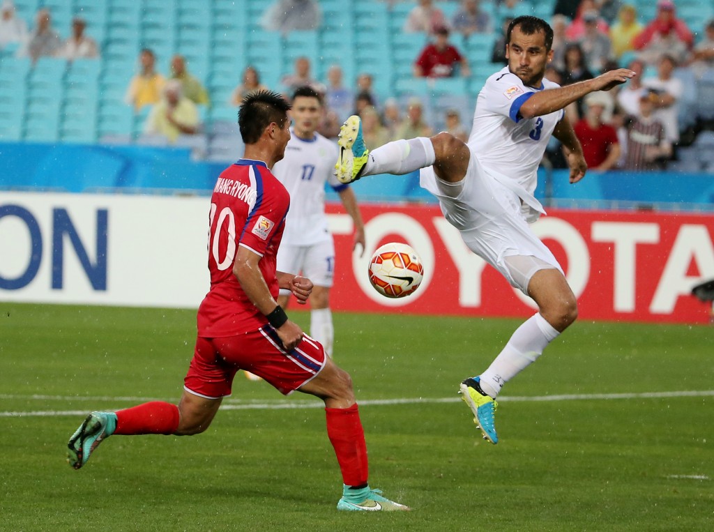 Uzbekistans Shavkatjon Mulladjanov kicks the ball as North Koreas Pak Kwang Ryong attempts to block during the first round soccer match of the AFC Asia Cup between Uzbekistan and North Korea in Sydney, Australia,  Saturday, Jan. 10, 2015. (AP Photo/Rob Griffith)