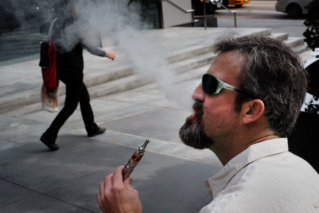 Paul Frohman smokes an electronic cigarette outside an office building in downtown Los Angeles on Wednesday, Jan. 28, 2015. California health officials  declared electronic cigarettes a health threat that should be strictly regulated like tobacco products, joining other states and health advocates across the U.S. in seeking tighter controls as "vaping" grows in popularity. (AP Photo/Richard Vogel)