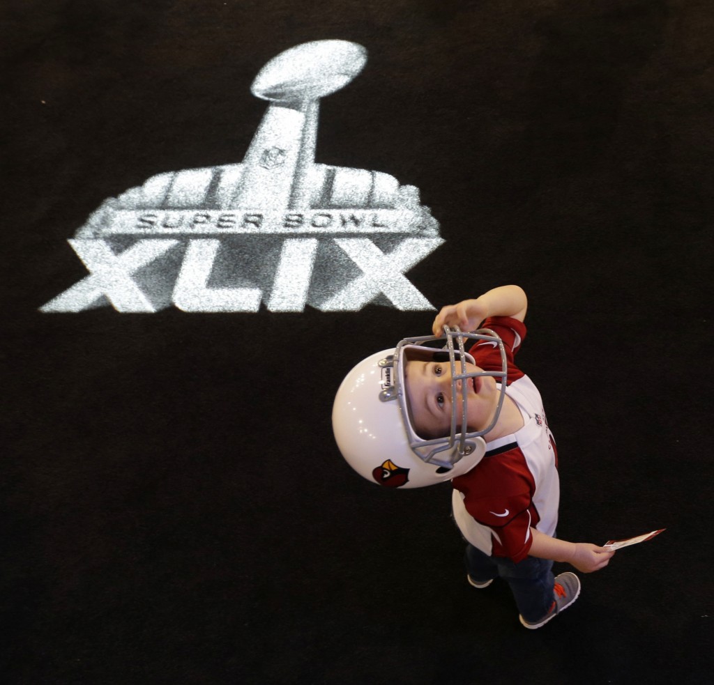 Two-year-old Kai Ezell-Tapia, from Phoenix, watches a video display at the Super Bowl XLIX NFL Experience Saturday, Jan. 24, 2015, in Phoenix. (AP Photo/Charlie Riedel)