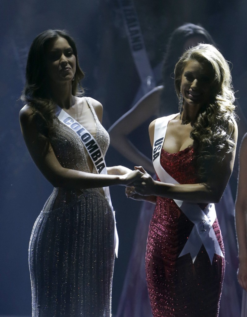 Paulina Vega of Colombia, left, and Nia Sanchez of the U.S., hold hands as the wait for the announcement of who will be selected as Miss Universe, Sunday, Jan. 25, 2015, during the Miss Universe pageant in Miami. (AP Photo/Wilfredo Lee)