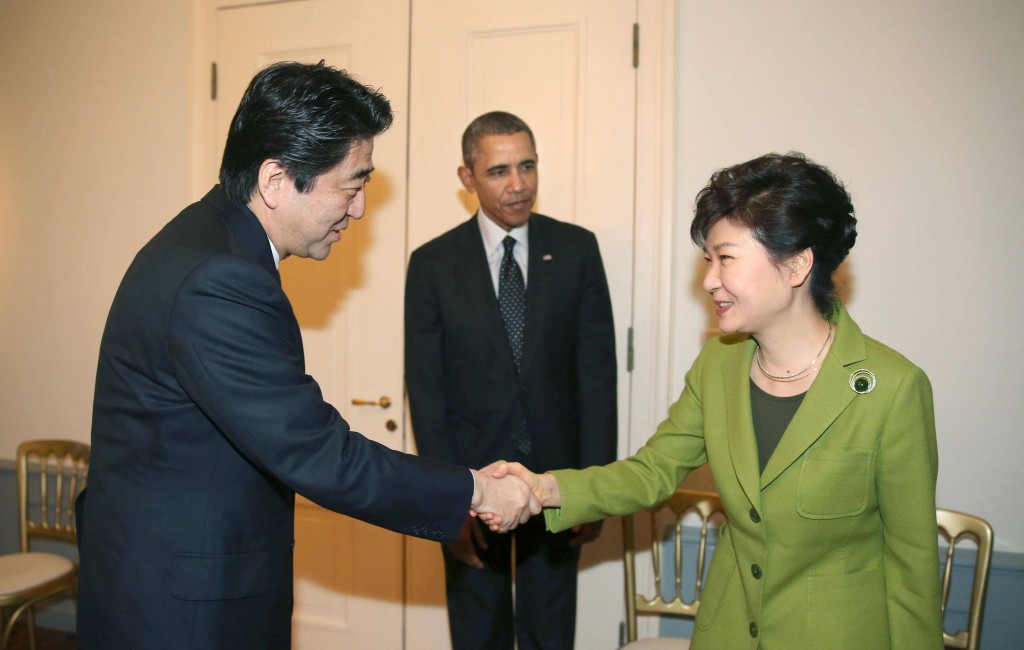 President Park Geun-hye and Japanese Prime Minister Shinzo Abe shake hands during a trilateral summit with President Barack Obama at the U.S. embassy in The Hague. (Yonhap)