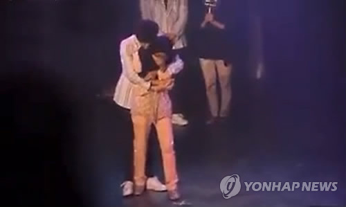 A Malaysian fan is hugged by a member of K-pop band B1A4 during a Kuala Lumpur fan event. (YouTube capture)
