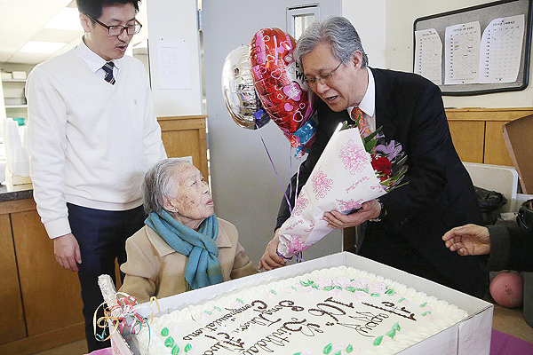 Pastor Yun Jong-hun delivers a cake and flowers as Song Wun-hwa celebrates her 106th birthday. (Korea Times file)