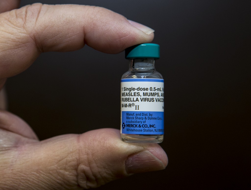 In this Thursday, Jan. 29, 2015 photo, pediatrician Charles Goodman holds a dose of the measles-mumps-rubella, or MMR, vaccine at his practice in Northridge, Calif. The vaccine is 99 percent effective at preventing measles, which spreads easily through the air and in enclosed spaces. Symptoms include fever, runny nose, cough and a rash all over the body. (AP Photo/Damian Dovarganes)