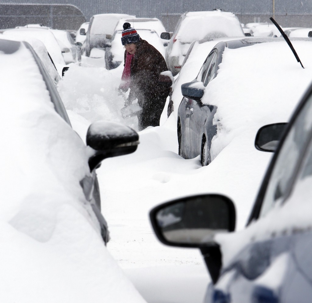 Mary Mulloy, of Strafford, Vt., works to dig her car out of the long term parking lot at the airport, Monday, Feb. 9, 2015, in Manchester, N.H. Mulloy was returning from Salt Lake City, where temperatures were in the 70s. (AP Photo/Jim Cole)