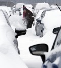 Mary Mulloy, of Strafford, Vt., works to dig her car out of the long term parking lot at the airport, Monday, Feb. 9, 2015, in Manchester, N.H. Mulloy was returning from Salt Lake City, where temperatures were in the 70s. (AP Photo/Jim Cole)