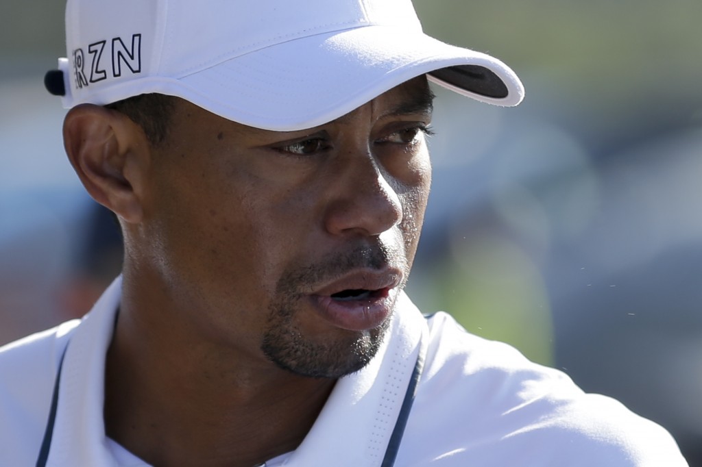 Tiger Woods looks back while loading his car after withdrawing in the first round of the Farmers Insurance Open golf tournament Thursday, Feb. 5, 2015, in San Diego. (AP Photo/Gregory Bull)