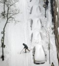 A snow shoveler tries to clear a spot in the middle of a city street beside snow-covered vehicles during a winter snowstorm Tuesday, Jan. 27, 2015, in Boston. Massachusetts was pounded by snow and lashed by strong winds early Tuesday as bands of heavy snow left some towns including Sandwich on Cape Cod and Oxford in central Massachusetts reporting more than 18 inches of snow. (AP Photo/Steven Senne)