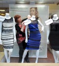Shop manager Debbie Armstrong adjusts a two tone dress in a window display of a shop in Lichfield, England, Friday Feb. .27, 2015. It's the dress that's beating the Internet black and blue. Or should that be gold and white? Friends and co-workers worldwide are debating the true hues of a royal blue dress with black lace that, to many an eye, transforms in one photograph into gold and white  (AP Photo/Rui Vieira)