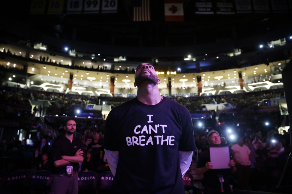 In this Dec. 9, 2014, file photo, Los Angeles Lakers' Carlos Boozer stands before team introductions for an NBA basketball game against the Sacramento Kings in Los Angeles. Dozens of athletes in recent weeks have responded to confrontations between authorities and black citizens in Ferguson, Mo., New York and elsewhere by wearing T-shirts bearing such statements as "I Can't Breathe" and "Hands Up, Don't Shoot!" The photo was part of a series of images by photographer Jae C. Hong which won the Thomas V. diLustro best portfolio award for 2014 given out by the Associated Press Sports Editors during their annual winter meeting in Orlando, Fla. (AP Photo/Jae C. Hong)