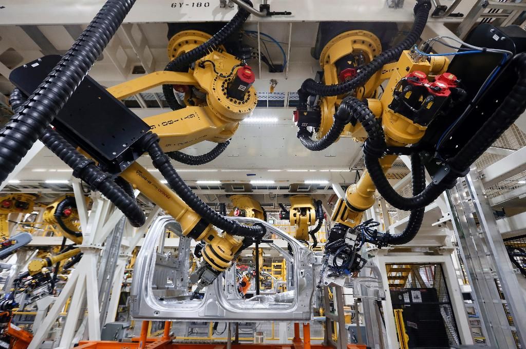 Robots install rivets on a 2015 Ford F-150 truck at the Dearborn Truck Plant in Dearborn, Mich. Cheaper, better robots will replace human workers in the world's factories at a faster pace over the next decade, pushing manufacturing labor costs down 16 percent, a report from the Boston Consulting Group said Tuesday, Feb. 10, 2015. (AP Photo/Paul Sancya)