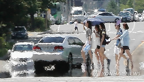 Citizens walk on a road in Yeouido, central Seoul, on Aug. 1, 2014, after the first heat wave warning of this year was issued in the capital area. The warning is usually issued if the daily high temperature is expected to rise above 35 C for two days in a row. (Yonhap)