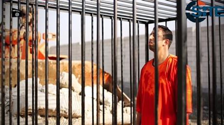 This still image made from video released by Islamic State group militants and posted on the website of the SITE Intelligence Group on Tuesday, Feb. 3, 2015, purportedly shows Jordanian pilot Lt. Muath al-Kaseasbeh standing in a cage just before being burned to death by his captors. The death of the 26-year-old pilot, who fell into the hands of the militants in December when his Jordanian F-16 crashed near Raqqa, Syria, followed a weeklong drama over a possible prisoner exchange. (AP Photo/SITE Intelligence Group)