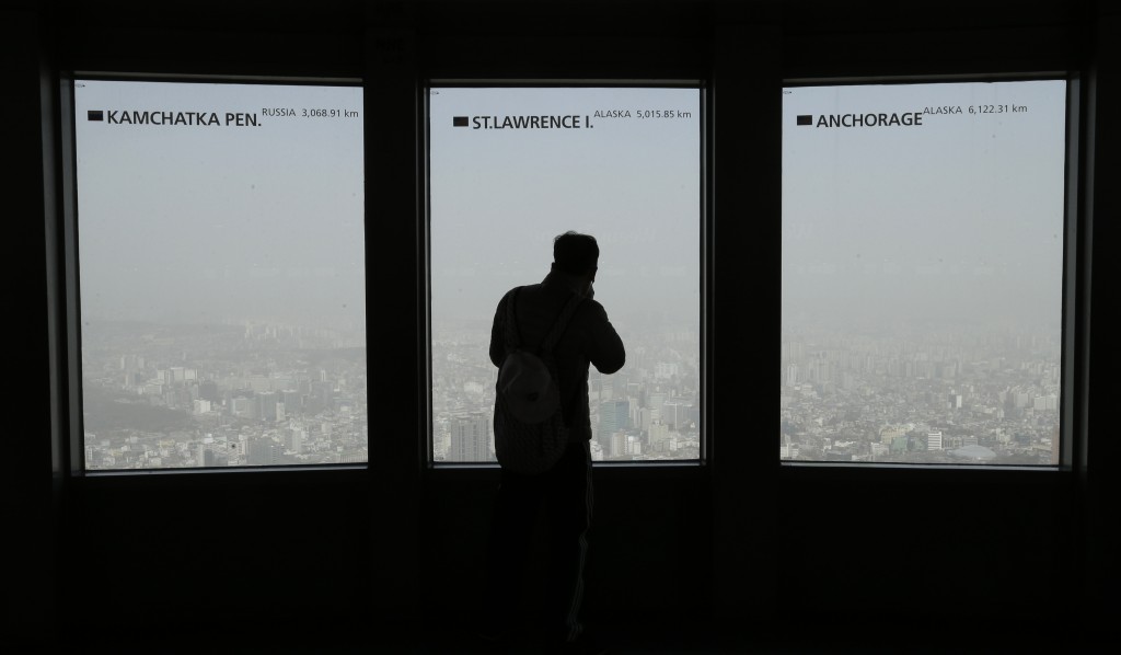 A man watches the city skyline covered with a thick haze caused by yellow dust at Seoul Tower's observation deck in Seoul, South Korea, Monday, Feb. 23, 2015. The Seoul metropolitan government issued a dust warning, urging people to stay indoors. ( AP Photo/Ahn Young-joon)