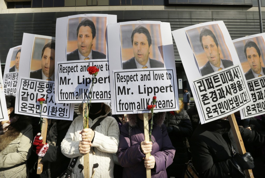 South Korean conservative activists hold portraits of U.S. Ambassador to South Korea Mark Lippert during a rally demanding his speedy recovery near the U.S. embassy in Seoul, South Korea, Friday, March 6, 2015. A knife attack Thursday that injured Lippert is the latest act of political violence in a deeply divided country where some protesters portray their causes as matters of life and death. The letters read " We love U.S. Ambassador to South Korea Mark Lippert and demand the alliance between South Korea and the United States" (AP Photo/Ahn Young-joon)