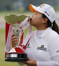 Park Inbee of South Korea kisses the trophy when prompted by organizers as she celebrates after winning the HSBC Women's Champions golf tournament on Sunday, March 8, 2015 in Singapore. (AP Photo/Wong Maye-E)