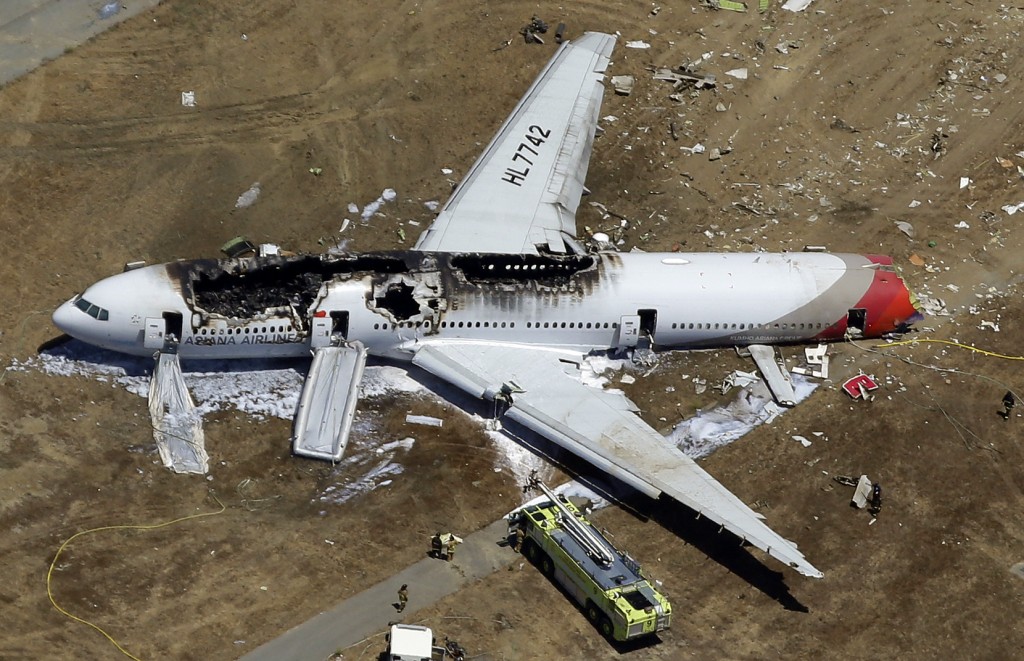 In this July 6, 2013, aerial file photo, the wreckage of Asiana Flight 214 lies on the ground after it crashed at the San Francisco International Airport in San Francisco. On Tuesday, March 3, 2015, more than 70 passengers aboard an Asiana Airlines flight that crashed in San Francisco two years ago have reached a settlement in their lawsuits against the airline. (AP Photo/Marcio Jose Sanchez, File)