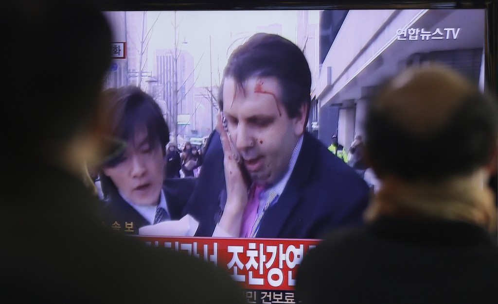 South Korean men watch a TV news program reporting U.S. Ambassador to South Korea Mark Lippert injured in a knife attack at Seoul railway station in Seoul, South Korea, Thursday, March 5, 2015. Lippert was slashed on the face and wrist by a man wielding a weapon with a 10-inch blade and screaming that the rival Koreas should be unified, South Korean police said. (AP Photo/Ahn Young-joon)